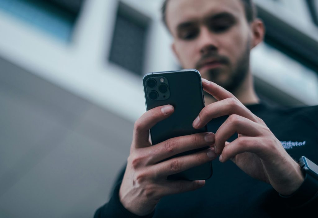 Man använder en mobiltelefon. Mobilen i bildens förgrund.