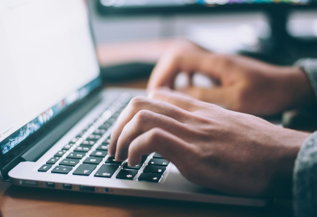 Ett par händer i närbild på en laptops tangenter.