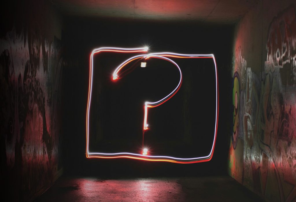 Ett ljust frågetecken på en mörk bakgrund.